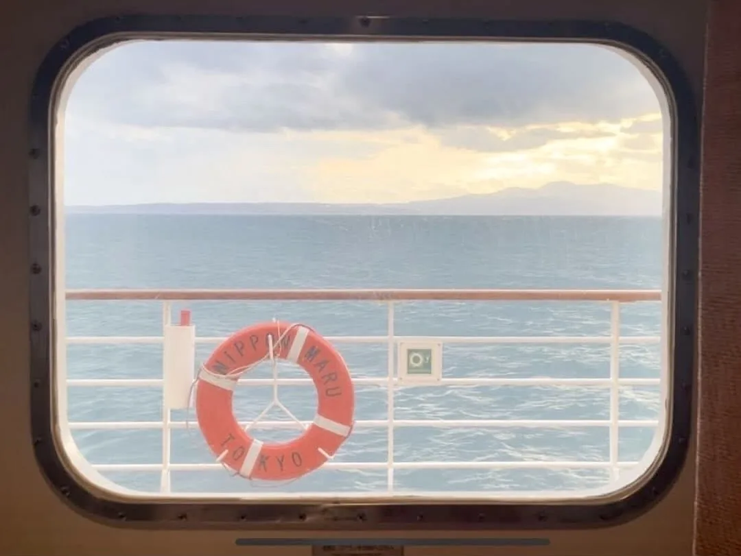 Vista del mar desde un ojo de buey del Nippon Maru, con un salvavidas con el nombre del barco